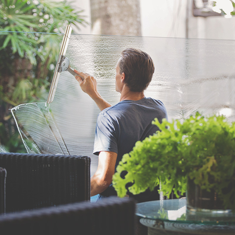 Un travailleur qui lave les vitres du balcon d'une terrasse